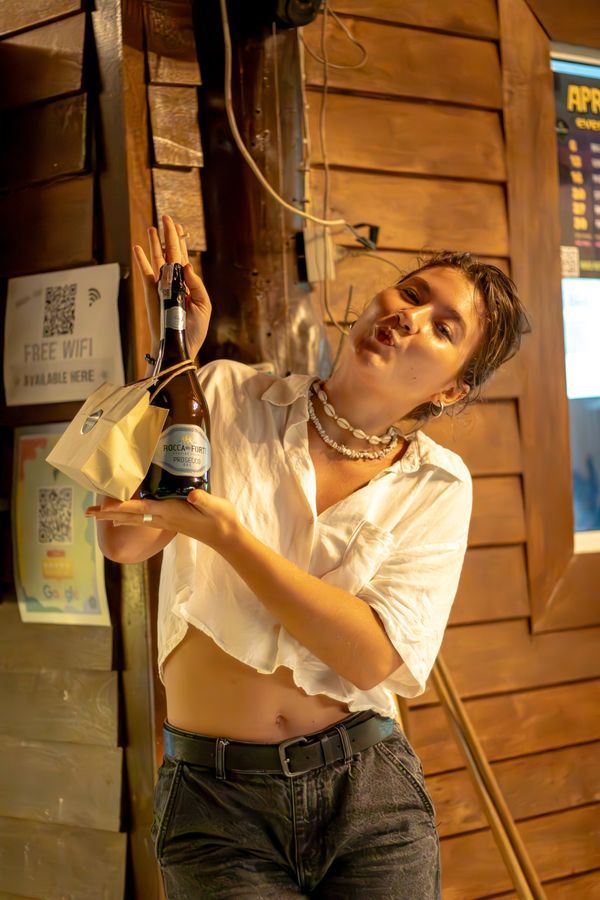 Guest holding a drink in front of the wood wall at MG Bistro, Ko Samui